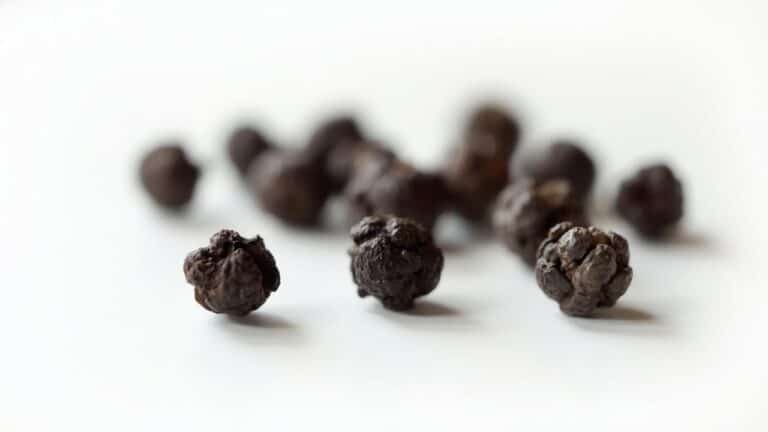 Gros plan sur des grains de poivre noir sur fond blanc